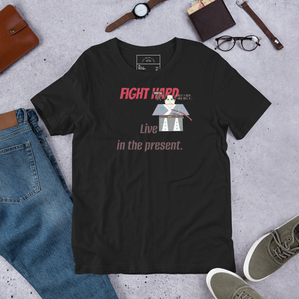 Black t-shirt with a playful samurai graphic and motivational text on a gray surface with jeans, shoes, and accessories.